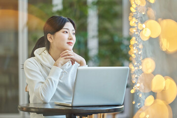 Young female college student model sitting at a cafe table in Asian Korea, listening to a lecture,...