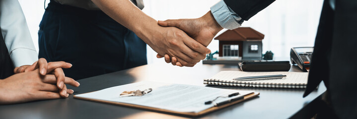 Client and real estate agent shake hand after signing house loan contract. Successful agreement for...