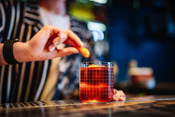 woman bartender hand making negroni cocktail. Negroni classic cocktail and gin short drink with sweet vermouth, red bitter liqueur