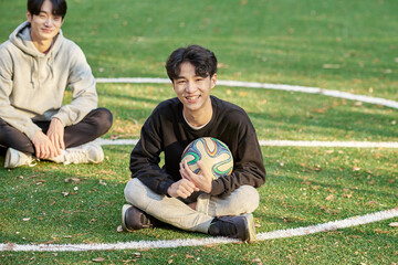 Two young college student male models sitting on futsal field in fall university of Asian Korea and...
