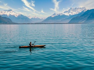 Person in a canoe navigating a tranquil mountain lake, taking in the majestic views