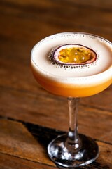 Exotic cocktail made with passion fruit, atop a wooden tabletop