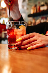 woman bartender hand making negroni cocktail. Negroni classic cocktail and gin short drink with sweet vermouth, red bitter liqueur