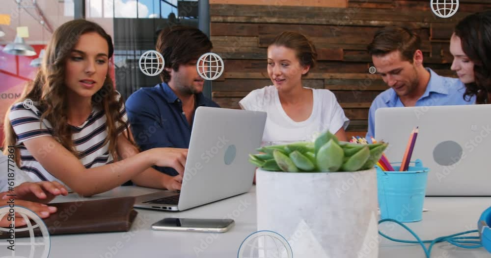 Poster animation of multiple globe icons over diverse coworkers discussing reports in meeting at office