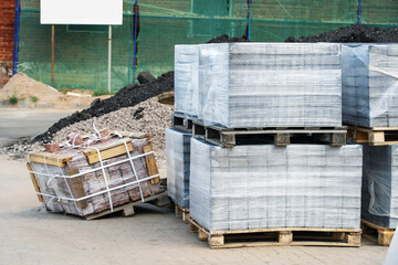 Paving stones on a pallet in plastic packaging at a construction site. Construction of footpaths...