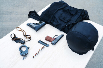 Outfit of a police officer or security guard. Bulletproof vest and firearms are on the table....
