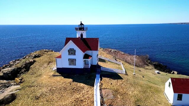 Drone over Nubble Lighthouse over rocky cliff vy the sea in York, Maine