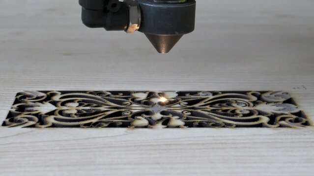 Traditional motifs engraved on wood with CNC laser machine. Image of computer-controlled cnc laser machine for engraving motifs on wood.