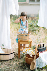 a girl in a blue dress stands in the yard with a bouquet of daisies
