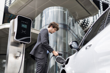 Below view closeup image of progressive black suit businessman recharge battery of his electric...