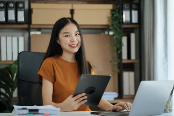 Female asian sitting at the desk, looking to camera.