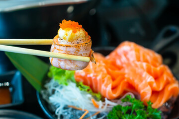 Eating Sushi with chopsticks. Sushi roll japanese food in restaurant.  with salmon, vegetables,...