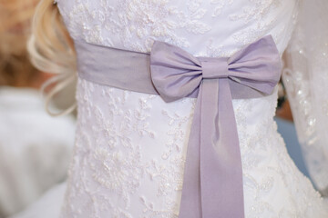 Obraz na płótnie Canvas Lilac belt with a bow at the waist of the bride's dress close-up