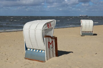 Strandkörbe am Strand der Nordsee in Cuxhaven bei Flut mit Wellen