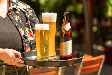 Close-up of beer on a tablet served by a waitress at a beer garden outdoor dining space ins ummer