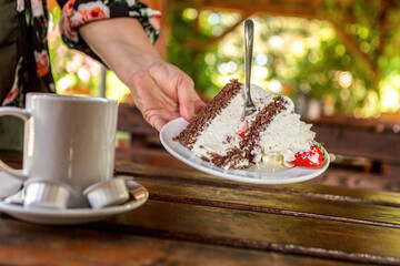 A waitress serving a piece of cake and coffee at an outdoor dining space in summer