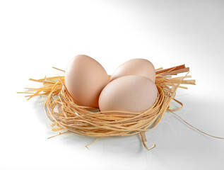 Three chicken eggs in a nest of straw close-up on a white background