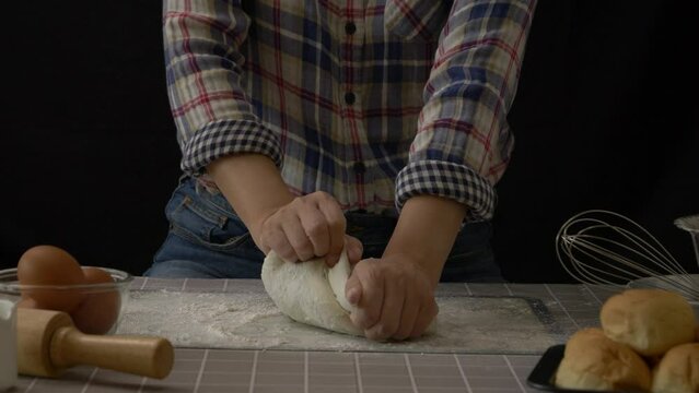 Artisan bread working with dough. Handmade bread kneading with flour splash in kitchen with bakery equipment tools, black background. Bread-making process for professional baker at work. slow motion