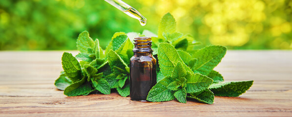 Peppermint essential oil in a small bottle. Selective focus. - obrazy, fototapety, plakaty