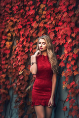 Generative AI illustration of Beautiful young caucasian woman with background of red leaves in autumn colors dressed in the latest fashion