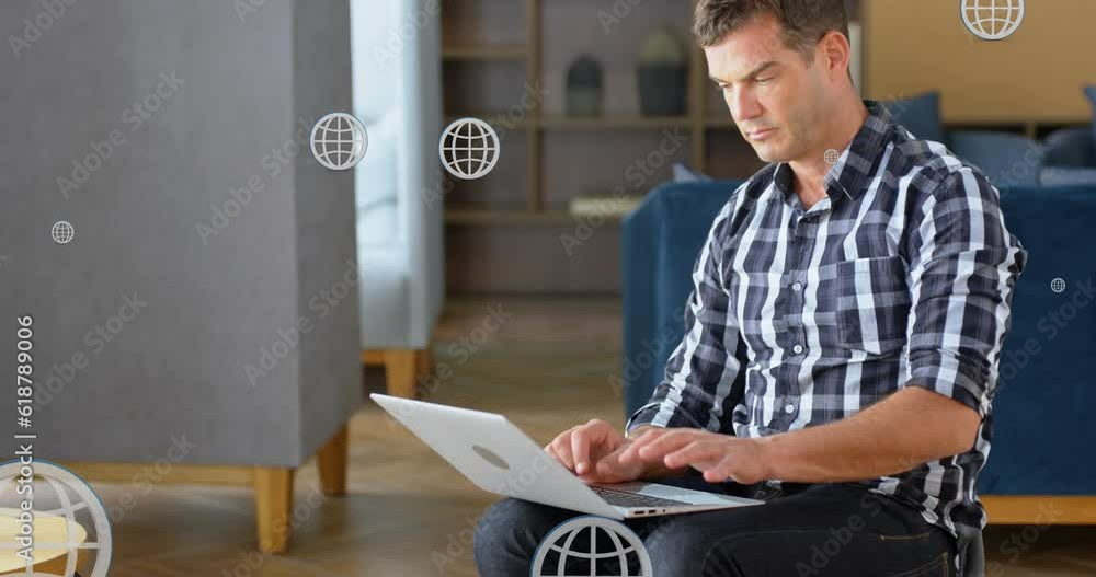Poster animation of multiple globe icons over caucasian man sitting on couch and working on laptop