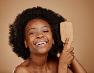Happy black woman, brush and hair care in studio, brown background and treatment of curly texture....