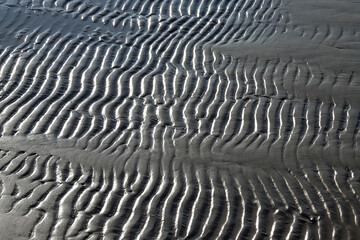 Sea beach. Ribbed sand texture in shallow water. Natural background.