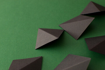 Black 3d triangle geometric shapes on green background, close up