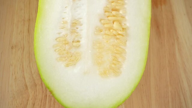 Macro video showcases the intricate details of a half Wax gourd, revealing its luscious flesh, delicate seeds, and textured rind. The probe lens captures the mesmerizing beauty within the fruit
