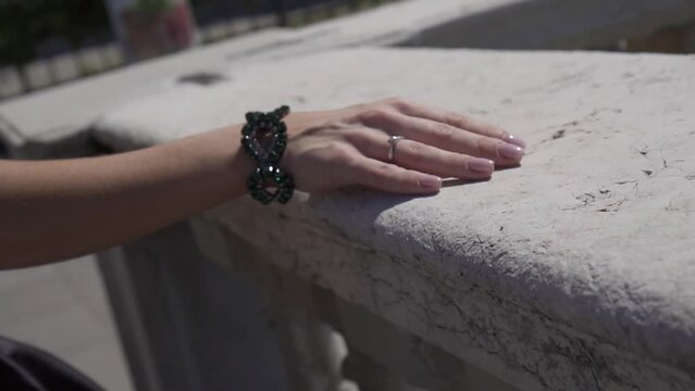 Girl's hand grazes the marble fence