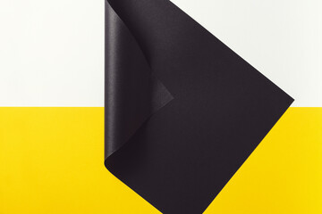 Folded black paper on yellow and white background.