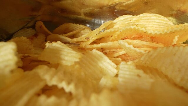 A captivating macro video captures the intricate details of a probe lens slowly gliding into a bag of potato chips, revealing the mesmerizing textures and colors of the chips up close. 4K
