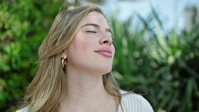 Young blonde woman breathing with closed eyes at park