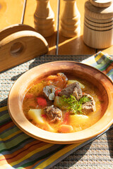 Meat soup with vegetables on a sunny day