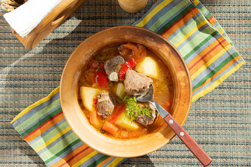 Meat soup with vegetables on a sunny day