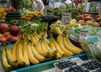 Stragan na placu targowym z owocami i warzywami. Banany, borówki, papryka, sałata.
