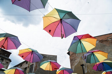 Kolorowe rozłożone parasole, zawieszone w powietrzu na tle jasnego nieba.
