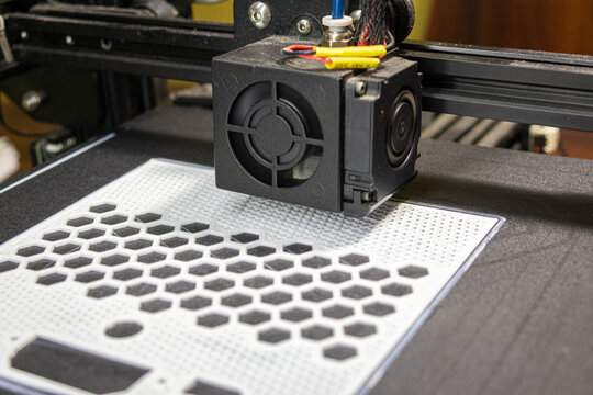A 3D printer printing a part of a robot with white pla filament