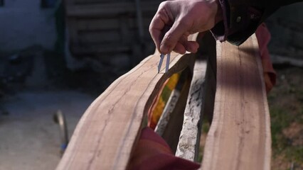 A master cabinetmaker marks with a compass on a half of a processed log for making a tool. Handicraft work. Individual entrepreneurship. Startup. Small family business