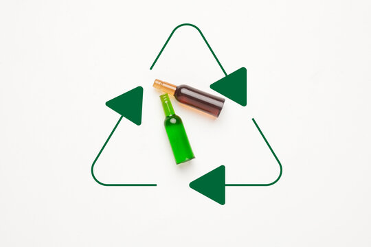 A flatlay picture of glass bottle miniature with recycle symbol on white background