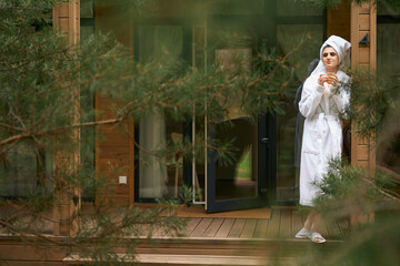 Woman in white coat drinking tea outside