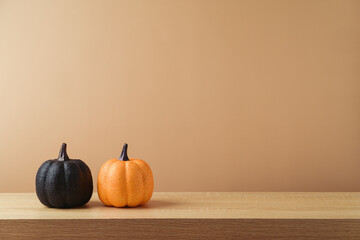 Autumn decoration concept with glitter orange and black pumpkin on wooden table over modern ...