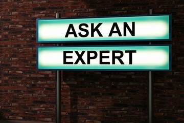 Fototapeta premium Ask an expert. Black letters on a blue illumintaed light box, red brick wall. Advice, decisions, expertise, knowledge, helping hand, skilled occupation, service. 3D illustration
