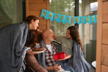 Pleased birthday person receiving gifts from his family