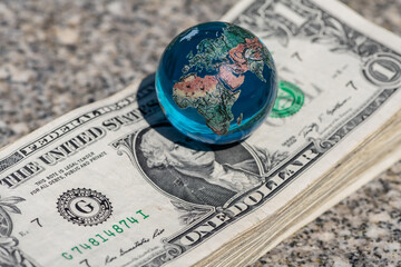 Glass miniature globe and stack of 1 US dollar bills