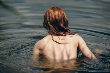 Back of of naked woman swimming in a lake - 618824234