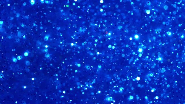 Blue and white floating particles shimmering in blue liquid. Shiny white pearls and bokeh chaotic movement. Illuminated sparkly glitter abstract moving background.