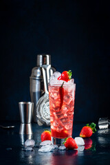 Red alcoholic cocktail drink with vodka, grapefruit juice, strawberries, sugar and hot chili pepper. Highball glass on dark blue background