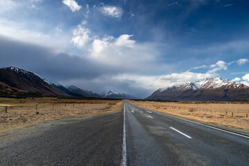 Scenic view along the Mount Cook Road alongside with snow capped Southern Alps basking in the late winter evening light. Best road trip route in New Zealand South Island with majestic Mount Cook. 