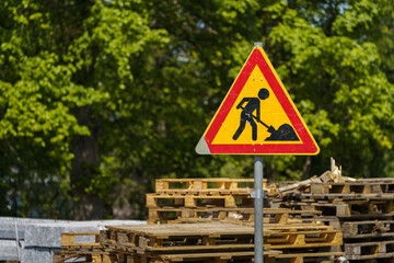 Roadworks warning sign with wooden pallets in the background. © OKemppainen
